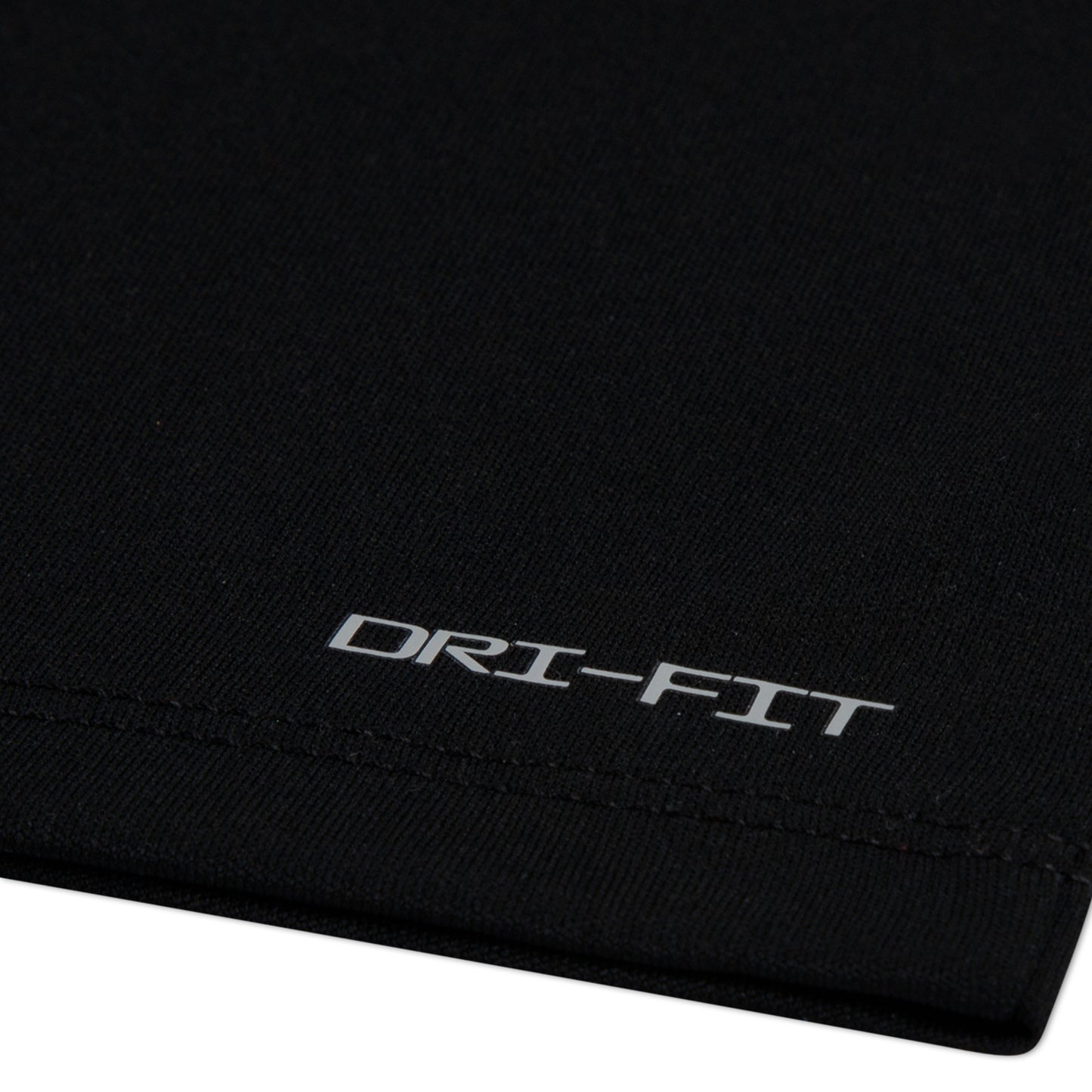 Détail de tissu noir en polyester avec inscription Dri-Fit, T-Shirt - Nike, vue rapprochée du matériau technique.