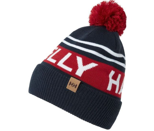 Tuque d'hiver - Helly Hansen tricotée en bleu marine et rouge avec pompon, pour enfant, vue en léger angle sur fond blanc.