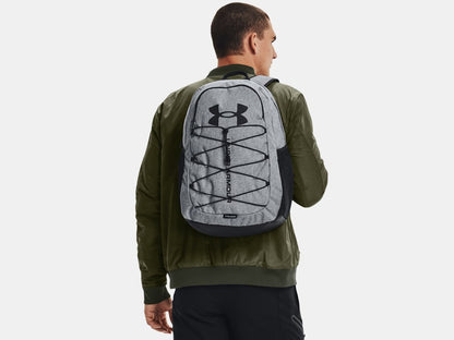 Sac à dos - Under Armour gris clair avec logo noir porté par homme de dos, style urbain, tissu imperméable visible